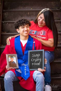 two people sitting on the steps, one is holding a sign and the other is wearing a graduation gown