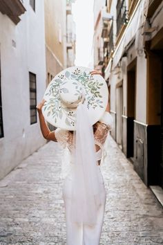 a woman is walking down the street with a hat on her head and veil around her neck