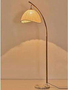 a floor lamp with a white shade on it's base and a beige background