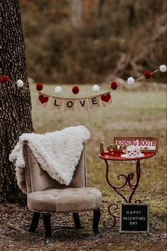 a chair sitting next to a tree with a sign that says i love kissing booth