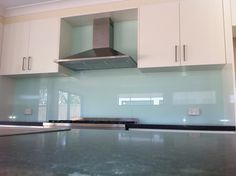 an empty kitchen with white cabinets and stainless steel stove top hood over the countertop