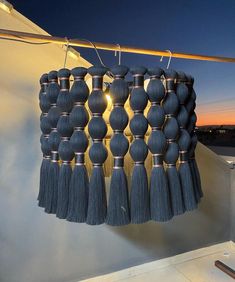 a wall hanging with tassels and lights on it's side in the evening