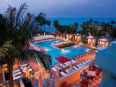 an aerial view of the pool and beach at night, with lounge chairs around it