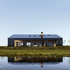 a house sitting on top of a lush green field next to a body of water