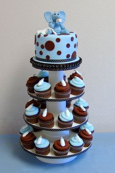 a three tiered cake with cupcakes on it and a teddy bear sitting on top