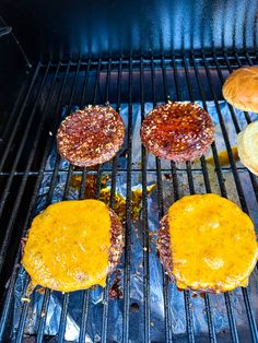 hamburgers cooking on top of a grill with buns next to them and cheese