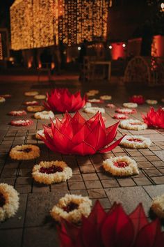 red paper flowers are on the ground in front of some white and gold decorations with lights behind them