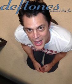 a man making a funny face while standing in front of a sign that says deftones