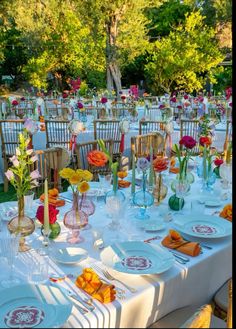 a table set up with plates and vases filled with colorful flowers on top of it