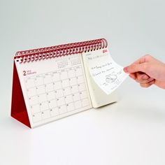 a hand holding a notepad next to a calendar