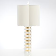 a table lamp with a white shade and gold trimmings on the bottom half