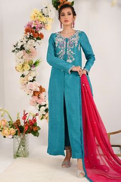 Steal the look this Eid by flaunting in our rosined which has intricate sitara floral embroidery followed with silver dabka, kora, water droplet pearls fine katdana and crystal work on neckline enhance with front open button down styled long silhouette shirt paired with vibrant fuchsine dupatta and straight pants. Shirt Fabric: Raw silk Shirt Length: 52” (customizable) Pant Fabric: Raw silk Dupatta Fabric: khadi net Shirt Color: teal blue Pant color: teal blue Dupatta Color: fuchsine All outfits Elegant Front Open Wedding Sets, Embellished Long Sleeve Traditional Wear For Eid, Embellished Traditional Wear With Long Sleeves For Eid, Embellished Traditional Wear For Eid, Embellished Long Sleeve Salwar Kameez, Designer Embellished Long Sleeve Salwar Kameez, Designer Long Sleeve Embellished Salwar Kameez, Embellished Fitted Kurta In Raw Silk, Traditional Embellished Front Open Sets