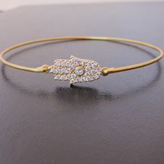 Hamsa Hand Bracelet - A gold plated Hamsa Hand with sparkling rhinestones has been transformed into a dainty & delicate Hamsa Hand bangle bracelet with a 14k gold filled bangle band. This rhinestone hamsa bangle can be stacked with other bangles from my collection. Have fun stacking your Hamsa Hand bracelet for the layered bangle look; http://www.etsy.com/shop/frostedwillow Please specify size in notes to seller during checkout for your Hamsa jewelry. Choose from one of my regular sizes belo Dainty Gold Bangle Crystal Bracelet, Adjustable Gold Crystal Bangle Bracelet, Gold Adjustable Crystal Bangle Bracelet, Adjustable Hand Set Gold Bangle Bracelet, Adjustable Hand-set Gold Bangle Bracelet, Adjustable Gold-plated Crystal Bangle Bracelet, Adjustable Hand Set Gold Bracelet, Hand Bracelet Gold, Hamsa Hand Jewelry