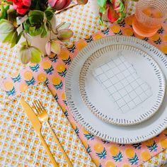 the table is set with plates, utensils and flowers