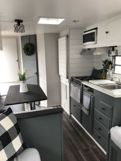 a kitchen and living room area in a mobile home with wood floors, white walls, and gray cabinets