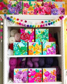 a shelf filled with lots of colorful boxes and balls of yarn