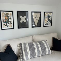 a white couch with pillows and pictures on the wall