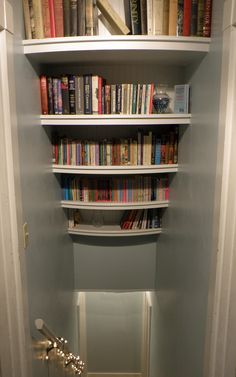 there is a book shelf with many books on it in the corner of this room