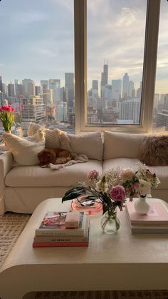 a living room with a couch, coffee table and large window overlooking the cityscape