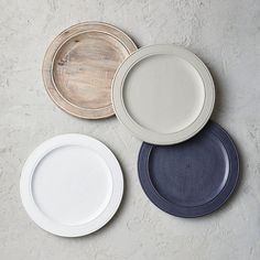 four plates with different colors on them sitting next to each other in front of a white wall