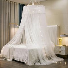 a canopy bed with white netting and fairy lights