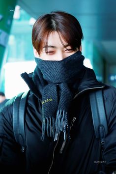 a young man wearing a black scarf and backpack