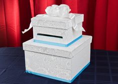 two white boxes with tissue paper on top of them sitting on a blue table cloth