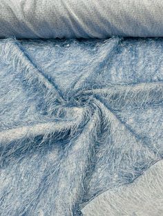 a blue and white blanket laying on top of a bed next to a gray pillow