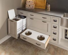 an open drawer in the kitchen with two bowls and one cat food dish on it