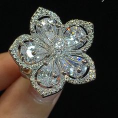 a woman's hand holding a diamond flower ring