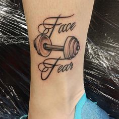 a woman's foot with a tattoo that says face fear and dumbbells