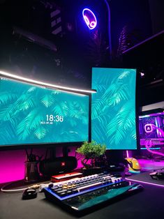 two computer monitors sitting next to each other on top of a desk in front of neon lights