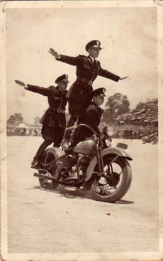 an old black and white photo of two men on a motorcycle with their arms outstretched