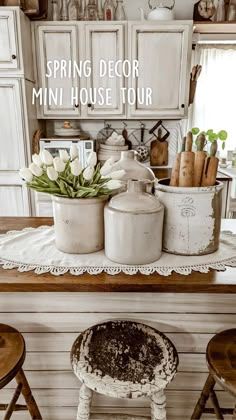 an old fashioned kitchen with white cabinets and wooden stools in front of the counter