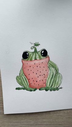 a drawing of a frog sitting on top of a piece of paper with watermelon