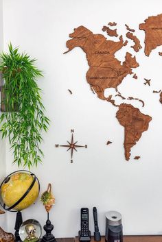 a wooden world map mounted on the wall next to a plant and other items in front of it