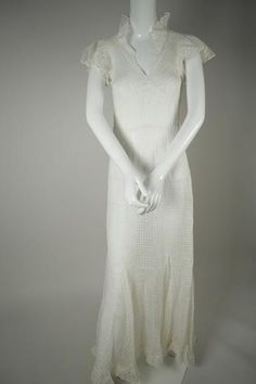 a mannequin wearing a white dress with ruffles on the shoulders and sides