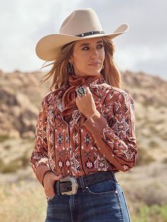 COUNTRY TO THE CORE A country fashion staple, Lainey loves Checotah shirts. Like a pair of Wranglers, they remind her of home. The Wrangler® x Lainey Wilson Chestnut Checotah Western Snap Shirt features a brown colorway with an earthy neutral pattern. It also has all the classic details you’d ever want in a Checotah, like the piped Western yokes, smile faux chest pockets, and pearl snap placket and cuffs. Lainey was hands-on in the creation of every collection piece, including this one. That’s w Wrangler Women's Outfit, Affordable Western Boutiques, 80s Country Fashion Women, Lainey Wilson Costume, Lainey Wilson Pictures, Lainy Wilson, Rodeo Fits, Ranch Outfits, Western Office