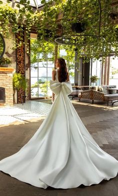 a woman in a white wedding dress standing on the floor with her back to the camera