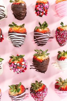 chocolate covered strawberries are arranged on a pink surface