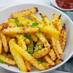 a white bowl filled with french fries and ketchup on top of a table