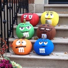 four pumpkins with faces painted on them sitting on the steps