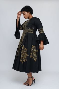 This one of a kind African made, gold embroidered masterpiece is sure to show off your elegance, class and hint of royalty. Going through a rigorous 3 step handcrafting process geared to make you feel like the queen you are! Front zipper Fully lined 51” long Black dress is made from stretch cotton and embroidered with gold silk Gold embroidery Limited stock Bell sleeves Could be worn as a dress or jacket Care instructions Hand wash with cold water Could be dry cleaned Low iron Elegant Fitted Dress With Gold Embroidery, Formal Gold Dress With Intricate Embroidery, Royal Long Sleeve Dresses With Intricate Embroidery, Royal Embroidered Fitted Dress, Gold Long Sleeve Dresses With Gold Embroidery, Fitted Long Sleeve Dress With Gold Embroidery, Elegant Long Sleeve Outerwear With Gold Embroidery, Fitted Embroidered Gold Dress, Fitted Gold Embroidered Outerwear