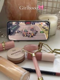 a table topped with makeup and cosmetics items next to a cell phone on top of a counter