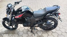 a black motorcycle parked on top of a cobblestone road