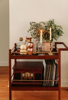 a wooden table topped with a radio next to a vase filled with flowers and candles