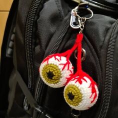 two crocheted eyeballs hanging from a backpack