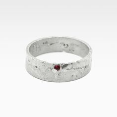 a silver ring with a red stone in it