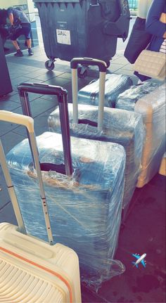 several pieces of luggage are wrapped in plastic and sitting on the floor at an airport