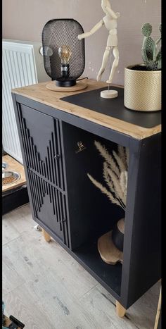 a black cabinet with some plants on top and a statue in the corner next to it